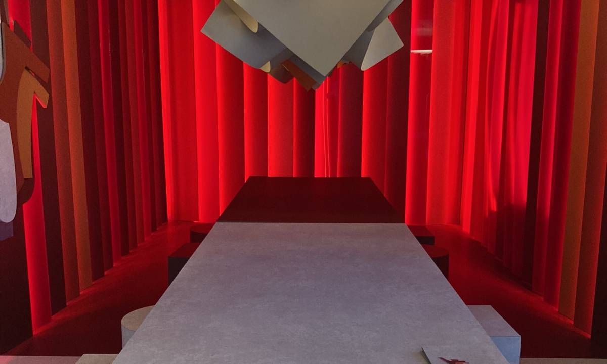 Insight_Casa Decor_Espacio rojo y gris con juego de mesa sillas taburetes y monocromático con luminaria abstracta y ambiente cálido