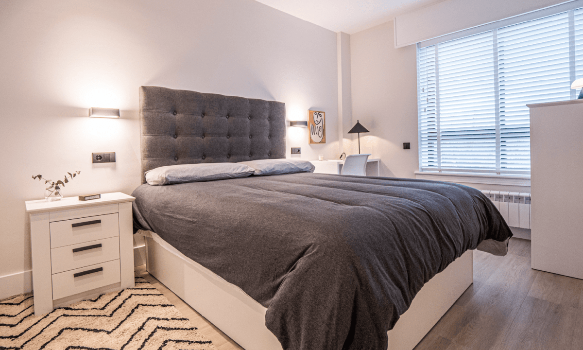 Apartamentos turísticos Montrove_Grid_Habitación dormitorio con cama en tonos grises, lámparas, textiles, ventana