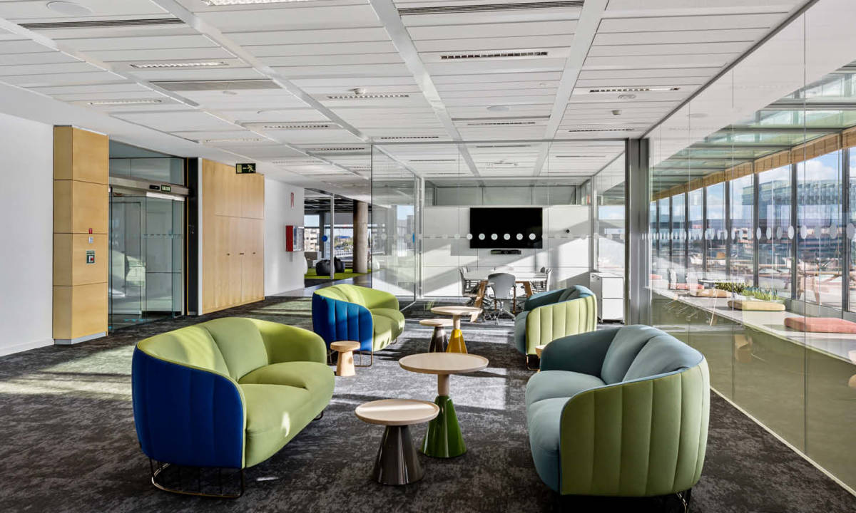 Zona de descanso en oficina moderna con colores verdes y azules y mobiliario
