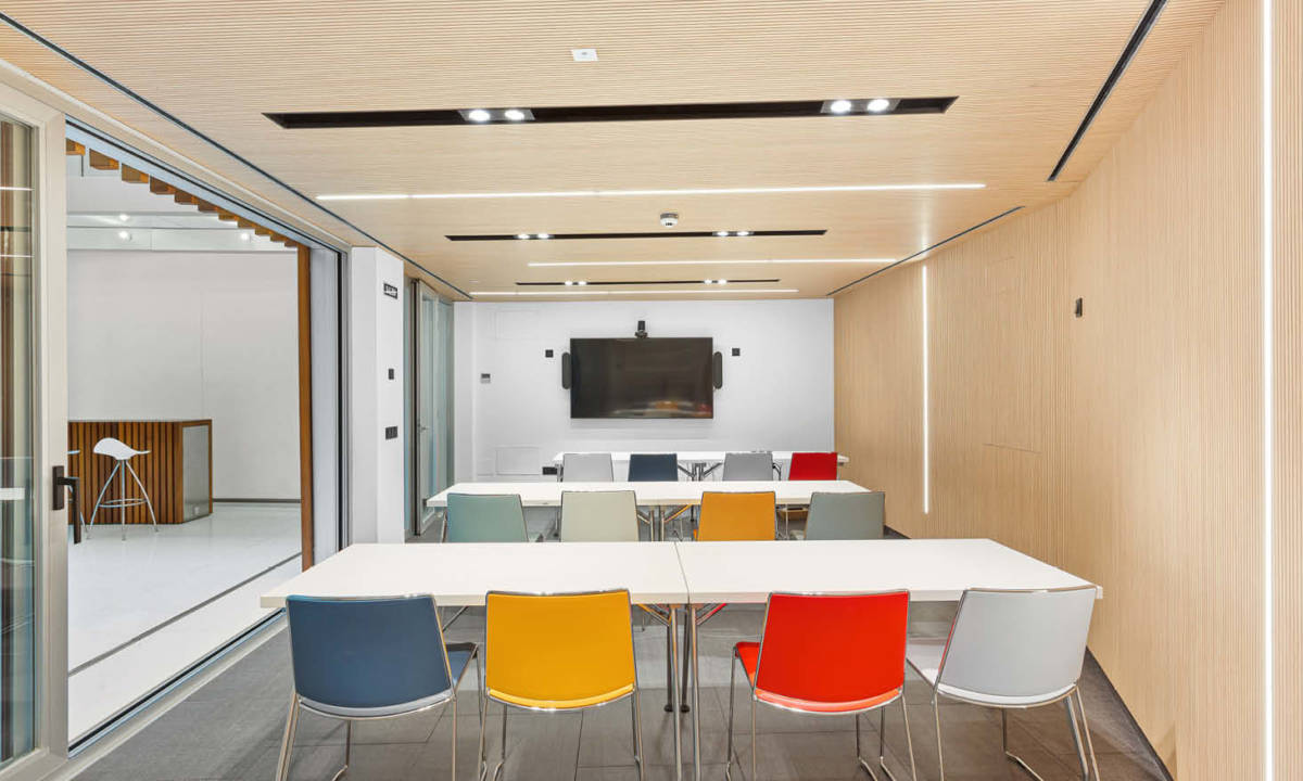Sala de reuniones en oficina, con mobiliario de colores y sala con tecnología para reuniones en común de equipo