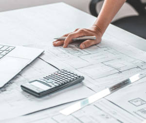 Técnico, arquitecto o ingeniero trabajando con planos y ordenador según metodología BIM, en una mesa de trabajo en oficina técnica