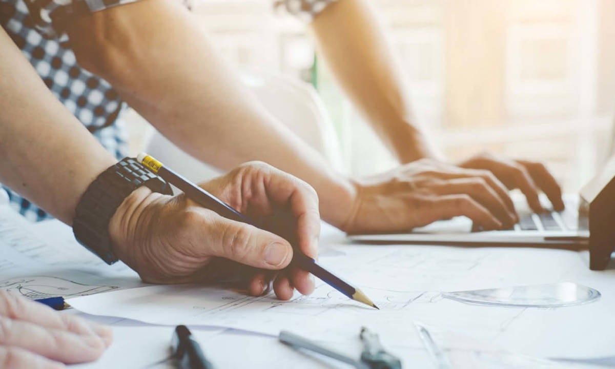 Técnicos trabajando en proyecto de construcción con planos en mesa