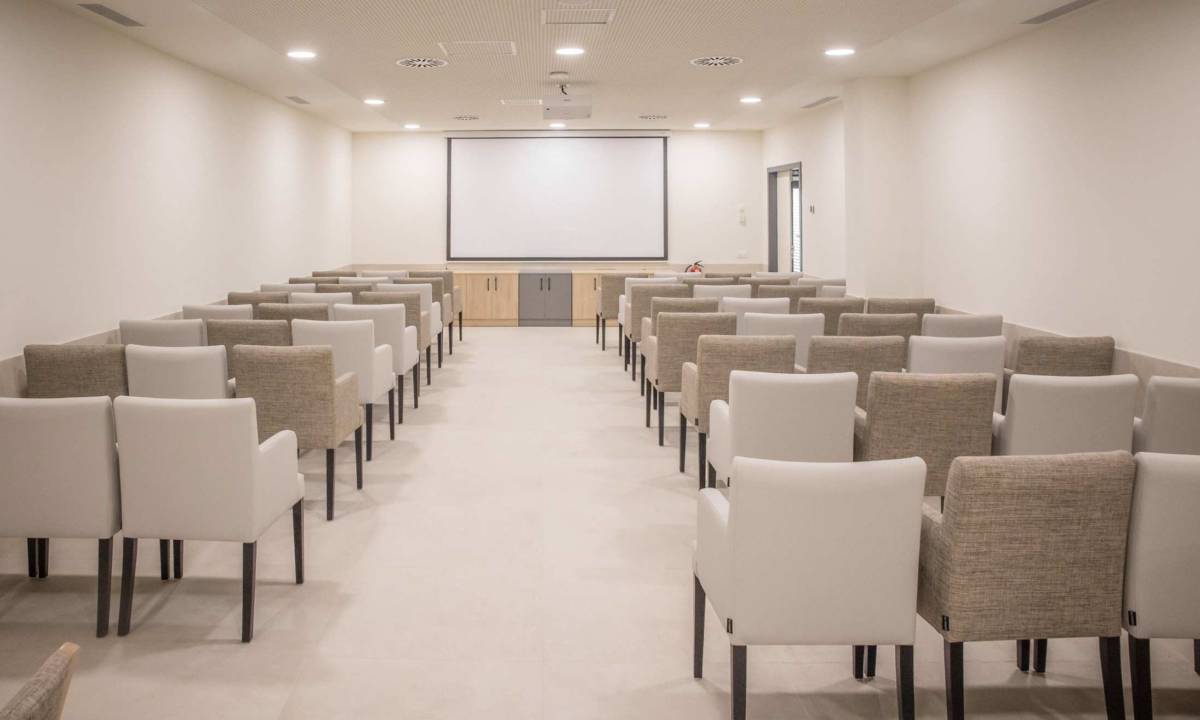 Sala de cine con butacas y proyector en residencia de mayores