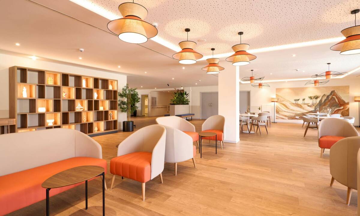 Salón de descanso en residencia de mayores con mobiliario de colores vivos y madera