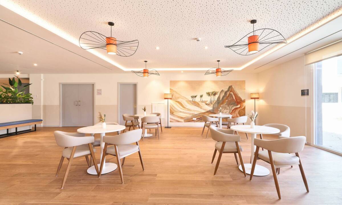 Zona de comedor con sillas, mesas, papel pintado e iluminación decorativa