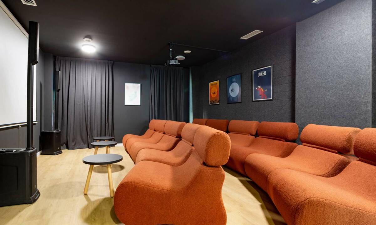 Sala de cine con sofás color caldero y pantalla de gran formato con proyector