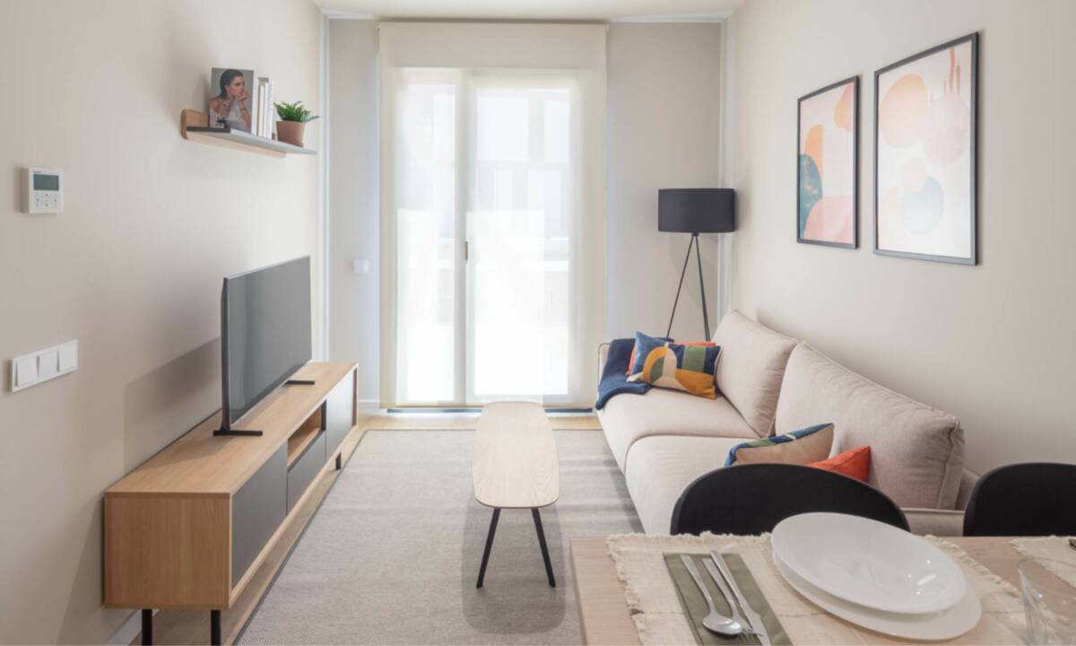 Salón cocina en apartamento compartido, con mobiliario seleccionado como sofá, mesa, luminarias y demás mobiliario auxiliar