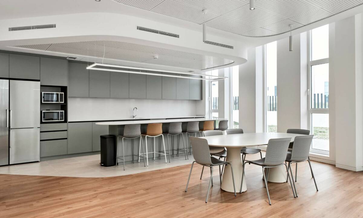 Zona de cantina con mobiliario de cocina a medida y sillas de colores