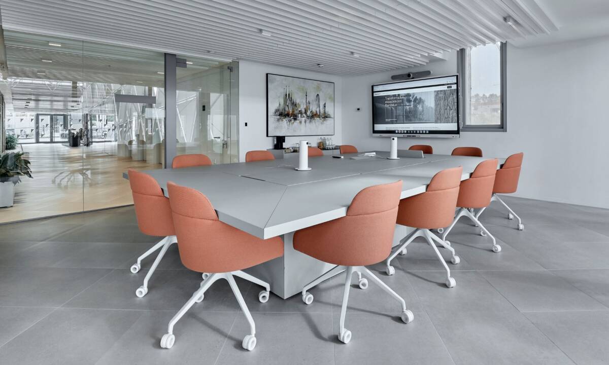 Sala de reuniones con sillas tapizadas en tela naranja y mesa de gran formato de carpintería a medida