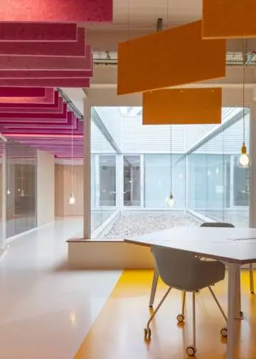 Espacio open space de puestos operativos en colores rosa y amarillo