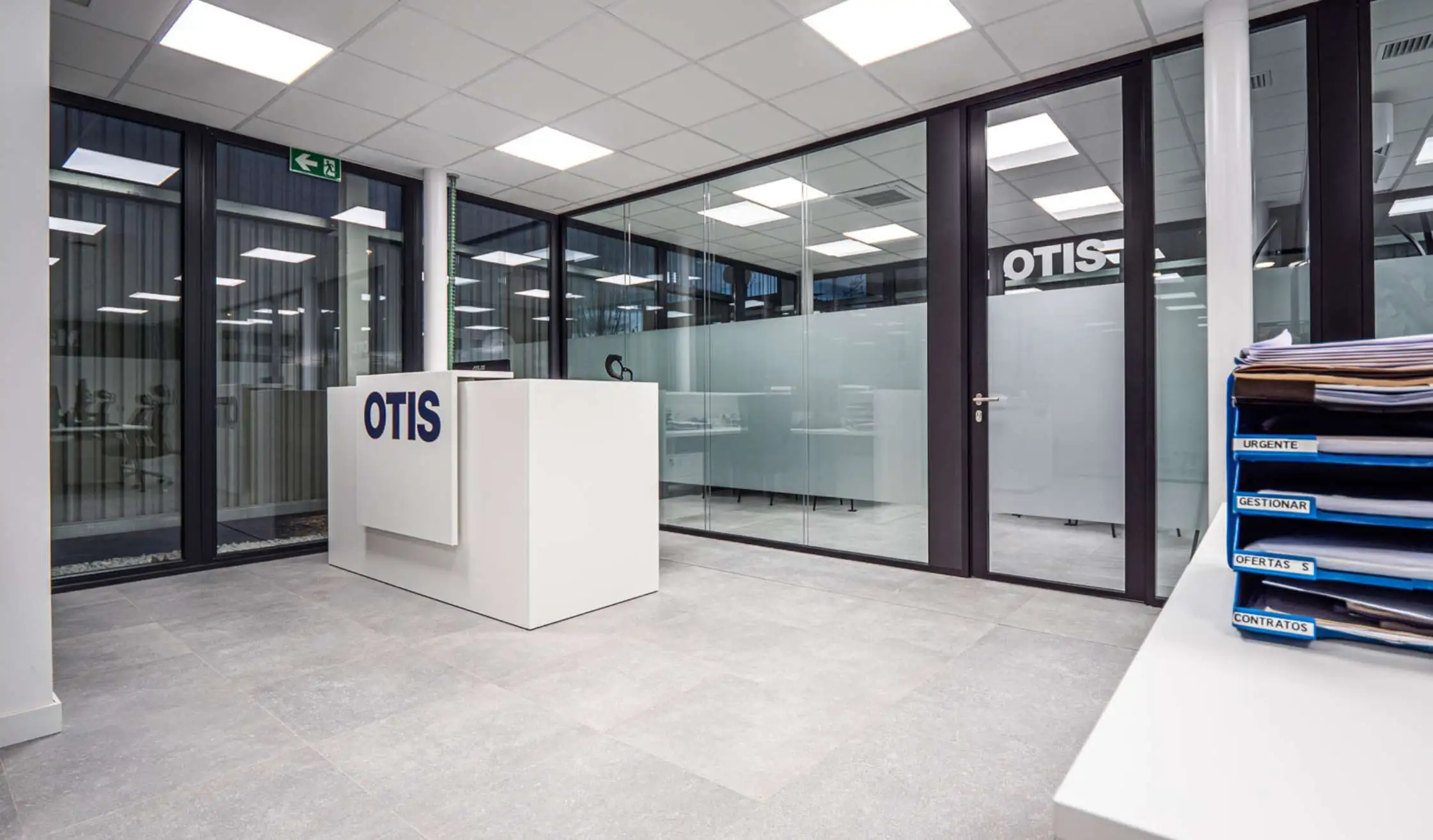 Zona de entrada de oficina con mostrador y mamparas de vidrio