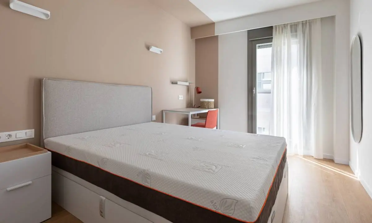 Habitación individual con cama, mesilla, escritorio y cortinas en Madrid
