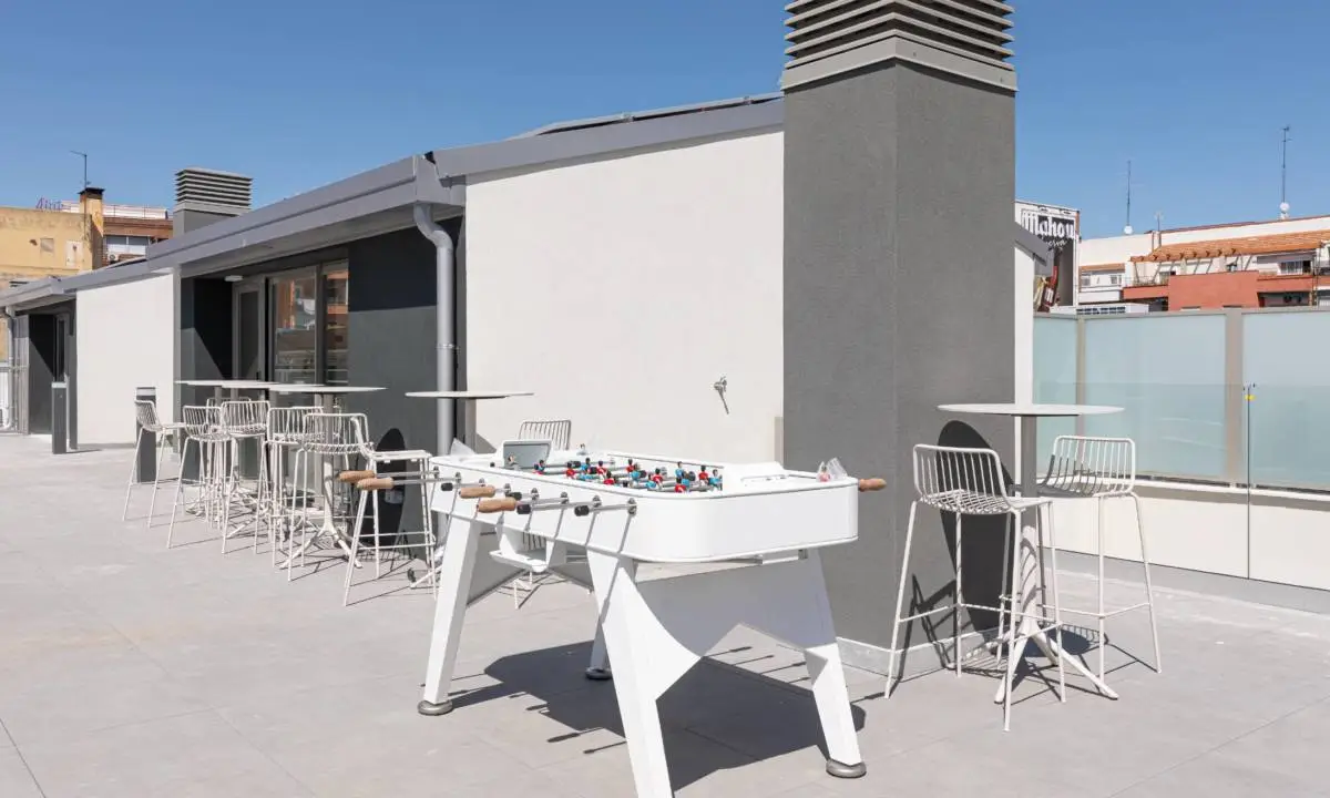 Zona exterior común de edificio coliving con futbolín y piscina