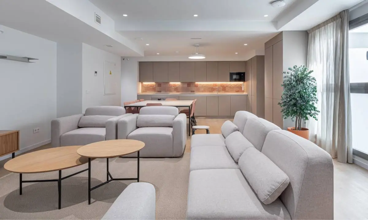 Salón común en edificio compartido con cocina, mobiliario de soft seating y vegetación