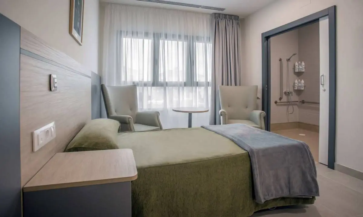 Dormitorio individual para mayores con cama, butaca y mobiliario a medida