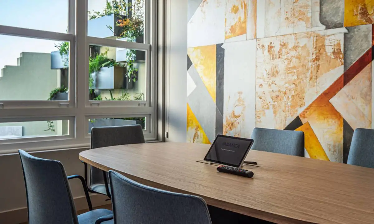 Espacio de reunión en oficina con pantallas audiovisuales y carpintería a medida