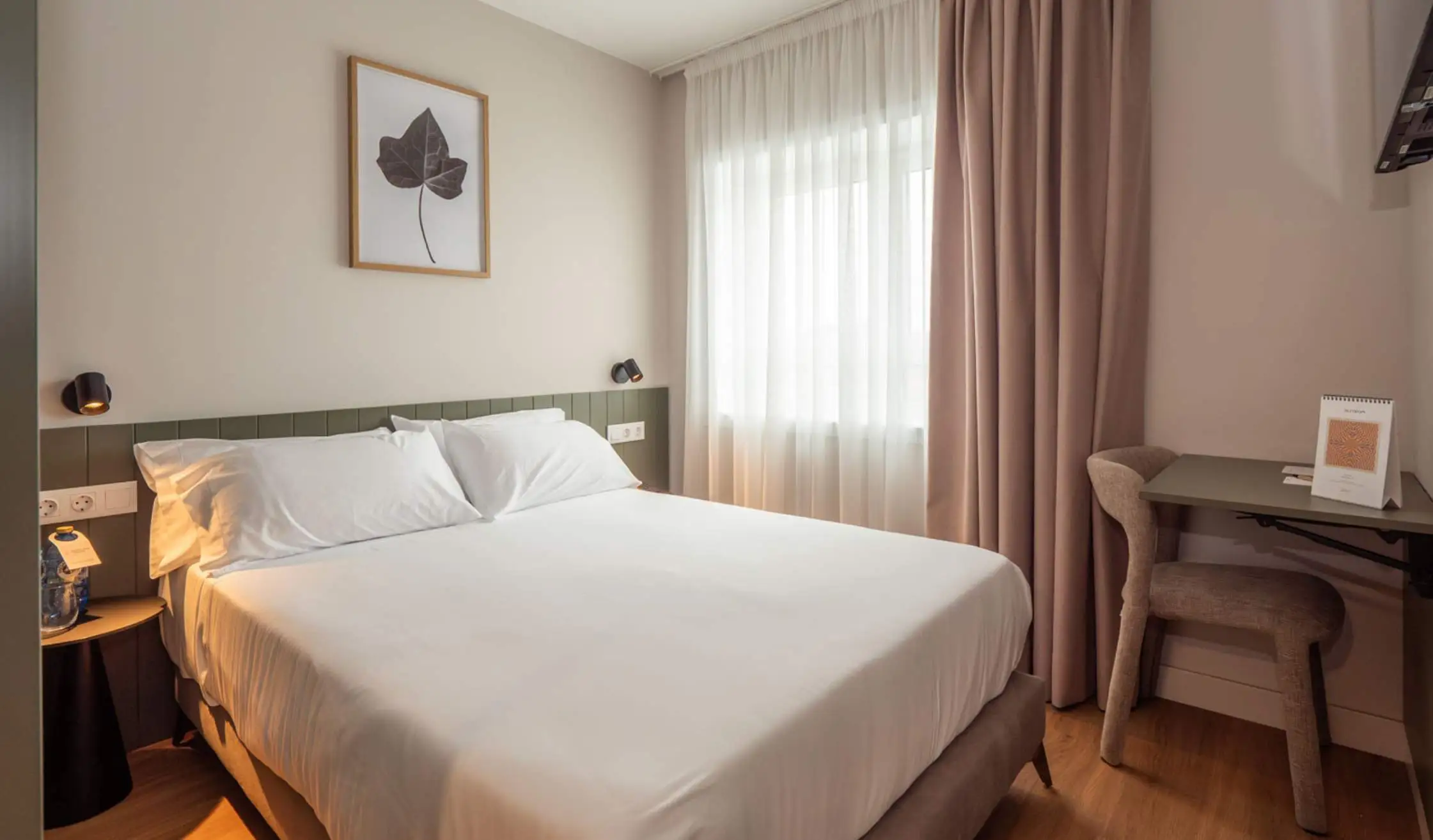 Cama de hotel doble con mobiliario y textiles seleccionados