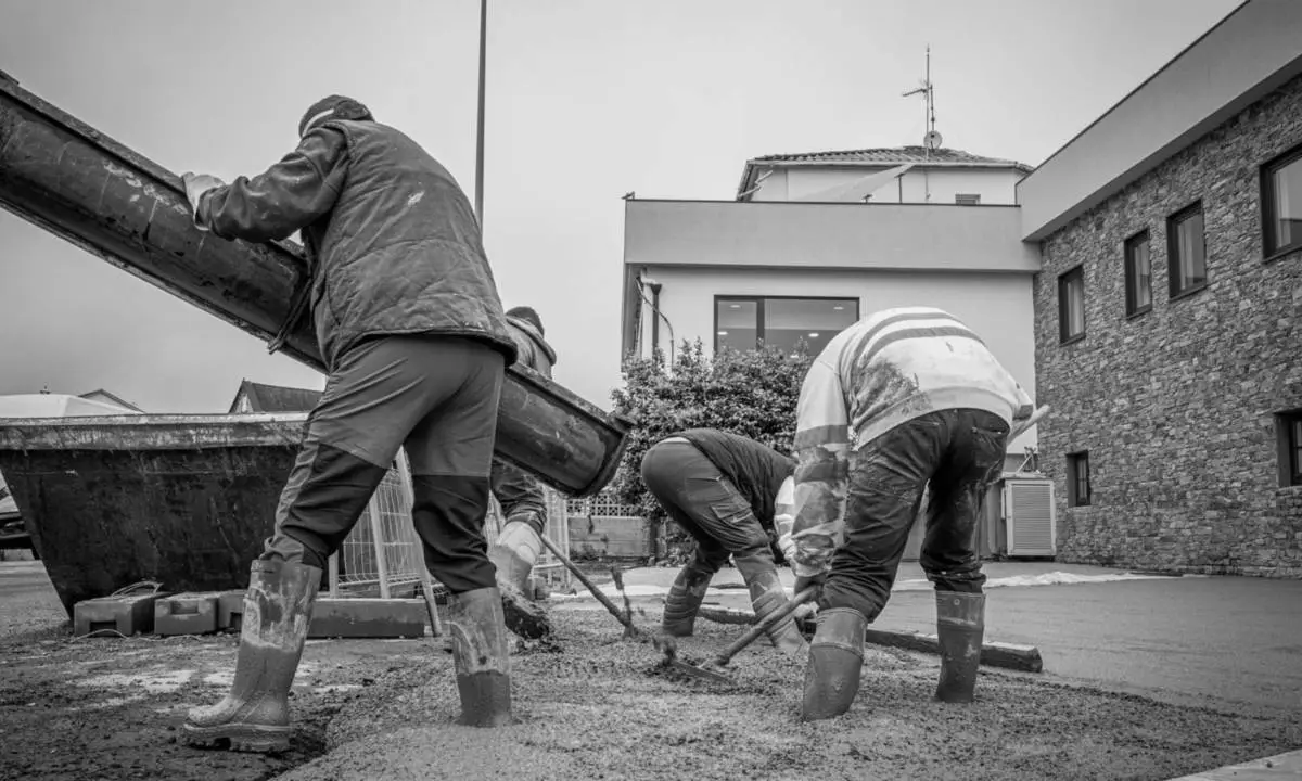 Trabajadores de obra realizando tareas de pavimentación exterior en hotel