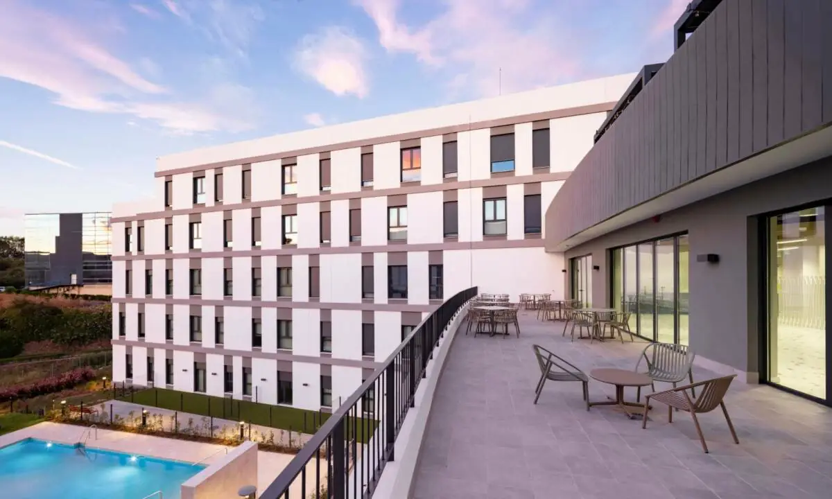 Zona exterior de espacio Coliving con piscina y mobiliario de exterior