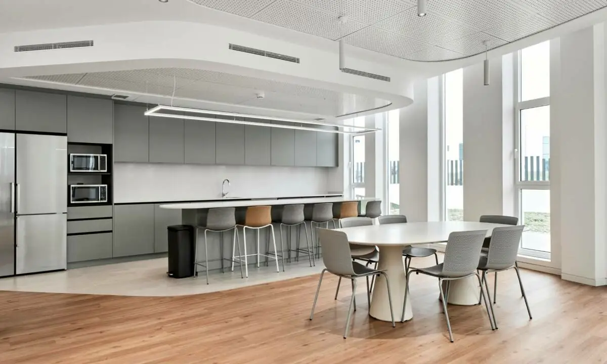 Zona de cantina con mobiliario de cocina a medida y sillas de colores