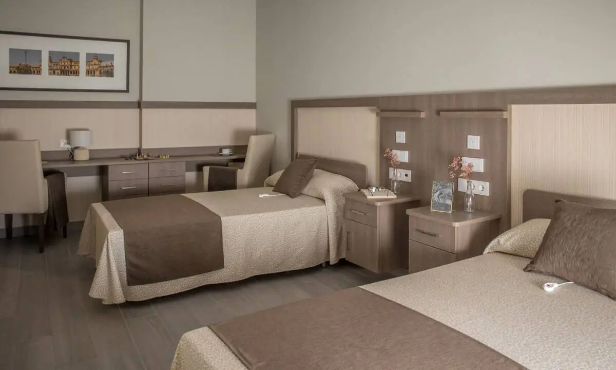 Dormitorio doble con textiles color marrón en residencia de mayores