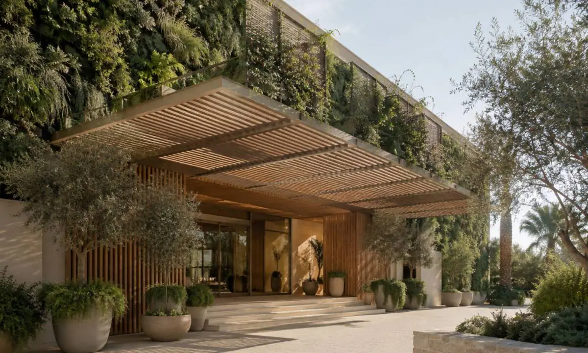 Entrada exterior de hotel con vegetación sobre entramado de madera y equipamiento sostenible