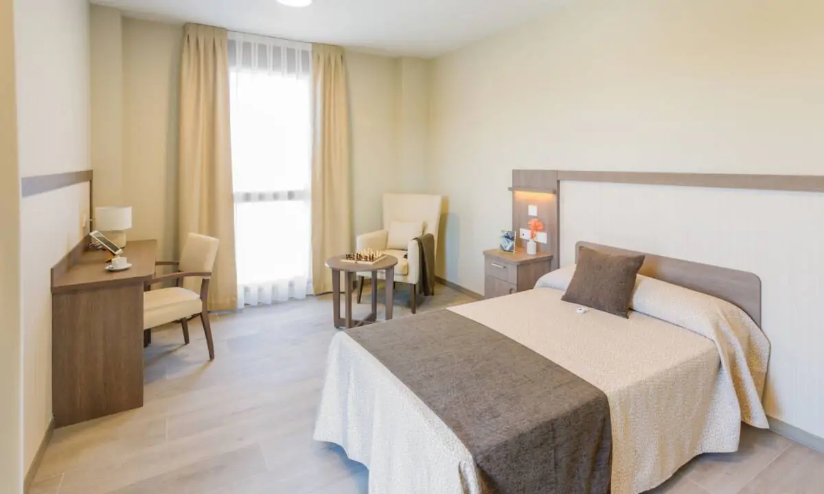 Habitación en residencia de mayores con mobiliario a medida y textiles en tonos marrones
